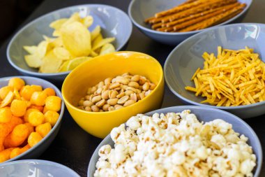 Koyu renkli masa üzerinde tuzlu abur cuburlar. Filmde patates cipsi, patlamış mısır, fıstık, peynir çubuğu, ketçap çubuğu, tzatziki cipsi, dumanlı fiske ve diğerleri yer alıyor.