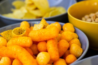 Koyu renkli masa üzerinde tuzlu abur cuburlar. Filmde patates cipsi, patlamış mısır, fıstık, peynir çubuğu, ketçap çubuğu, tzatziki cipsi, dumanlı fiske ve diğerleri yer alıyor.