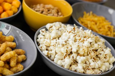 Koyu renkli masa üzerinde tuzlu abur cuburlar. Filmde patates cipsi, patlamış mısır, fıstık, peynir çubuğu, ketçap çubuğu, tzatziki cipsi, dumanlı fiske ve diğerleri yer alıyor.