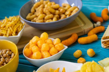 Ahşap masada bira tuzlu atıştırmalıklar. Koyu renkli masa üzerinde tuzlu abur cuburlar. Filmde patates cipsi, patlamış mısır, fıstık, peynir çubuğu, ketçap çubuğu, tzatziki cipsi, dumanlı fiske ve diğerleri yer alıyor.