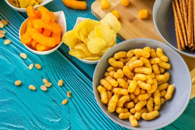 Ahşap masada bira tuzlu atıştırmalıklar. Koyu renkli masa üzerinde tuzlu abur cuburlar. Filmde patates cipsi, patlamış mısır, fıstık, peynir çubuğu, ketçap çubuğu, tzatziki cipsi, dumanlı fiske ve diğerleri yer alıyor.