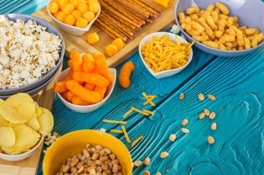 Ahşap masada bira tuzlu atıştırmalıklar. Koyu renkli masa üzerinde tuzlu abur cuburlar. Filmde patates cipsi, patlamış mısır, fıstık, peynir çubuğu, ketçap çubuğu, tzatziki cipsi, dumanlı fiske ve diğerleri yer alıyor.