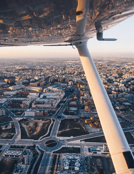 Vue de l'aile d'un petit avion survolant la ville au coucher du soleil. — Photo