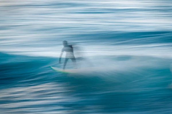 Silueta borrosa de un surfista en una ola. Concepto de movimiento y velocidad —  Fotos de Stock