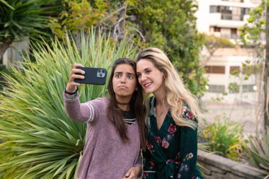 İki genç kız cep telefonuyla selfie çekiyor. Sosyal ağlarda arkadaşlık kavramı