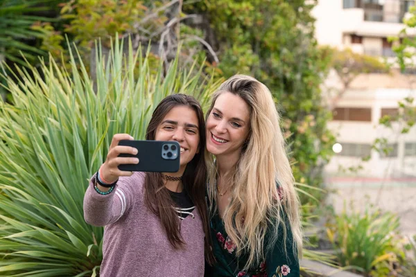 İki genç kız cep telefonuyla selfie çekiyor. Sosyal ağlarda arkadaşlık kavramı