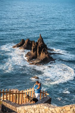 Genç mutlu çift köpekleriyle birlikte gün batımının tadını çıkarıyor.
