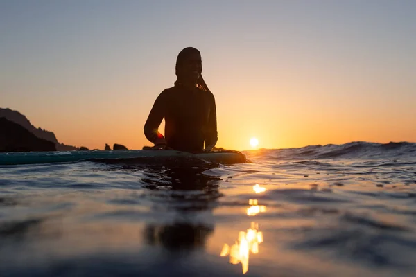 冲浪姑娘在日落时在水里等波浪 高质量的照片 — 图库照片