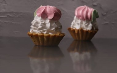 Gri arka planda krem şantili iki kek.