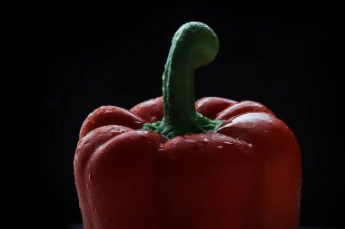 Red bell pepper with water drops isolated on black background