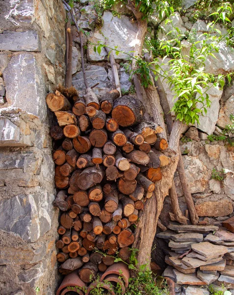 Stack of firewood in a garden next to the stonewall. Vertical and close up.
