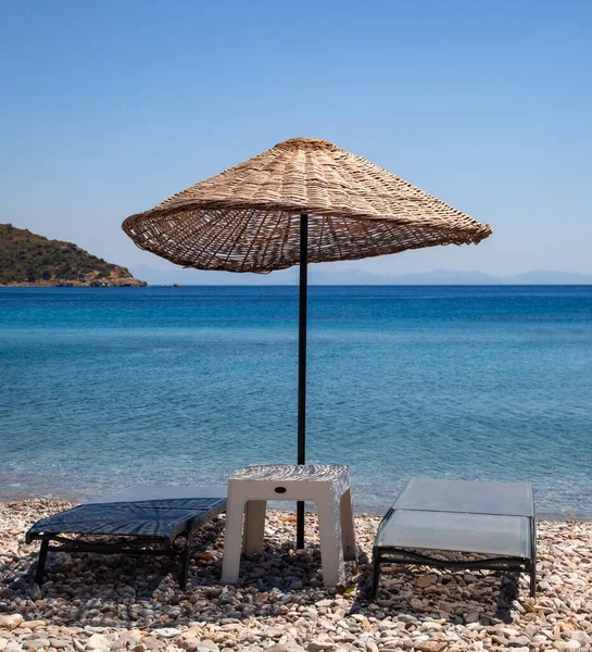 Wicker sunshade parasol and two empty sun loungers on the beach. Holiday concept. Landscape