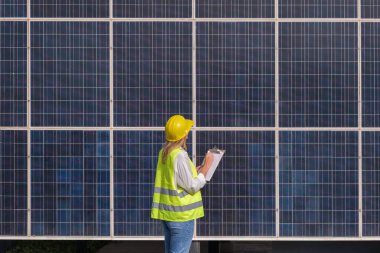 Kadın mühendis güneş panelini kontrol ediyor.