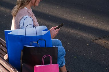 Alışveriş sonrası akıllı telefonunu kullanan genç bir kadın.