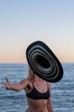 Yüzü örtülü kadın şapkasını havaya fırlatıyor.