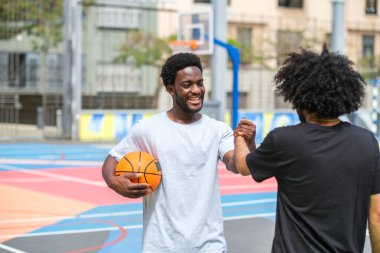 Basketbol sahasında kahkahalar atan afro saçlı iki genç.