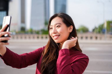 Güçlü bir kadın finans bölgesinde selfie çekiyor.