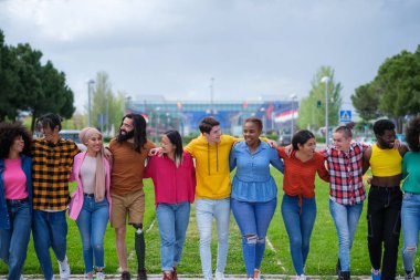 Farklı etnik kökenlere sahip bir grup insan birlikte yürüyor ve eğleniyor.