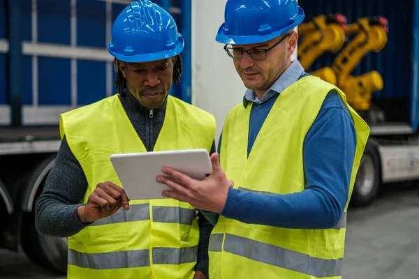 Two machine engineers reviewing the operation of the factory on their tablet