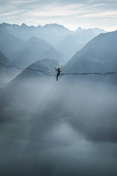brave woman on slackline in mountains over lake