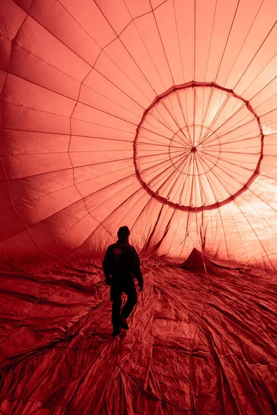 man walking inside illuminated red hot-air balloon
