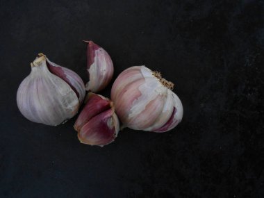 Kırmızı sarımsak, siyah arka planda, üst tarafta.