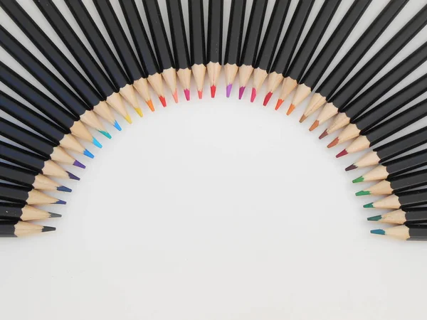 Beyaz arkaplan üzerinde yarım daire şeklinde dizilmiş renkli kalemler ve metin için boşluk