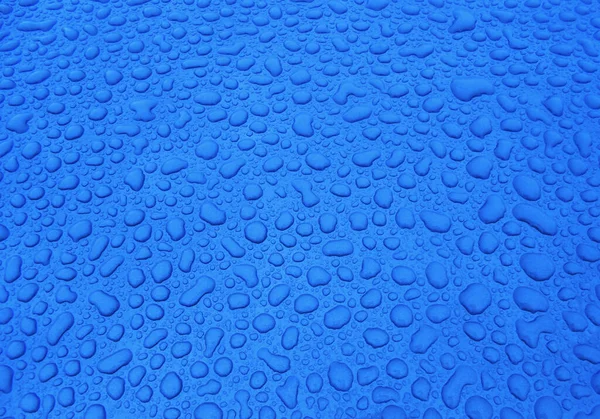 Mavi cam yüzeyde su damlaları