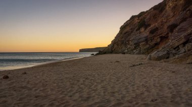 Sunset at portuguese beach with rocks in the background