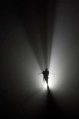 Silhouette of a man, in the rays of light at foggy night