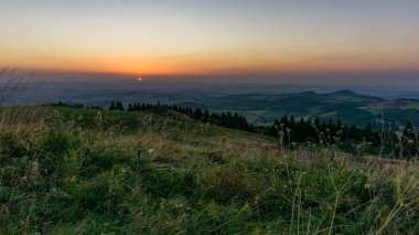 Sunset from Wasserkuppe, the highest point in Roehn Mountains with meadow in foreground under a clear sky, Germany