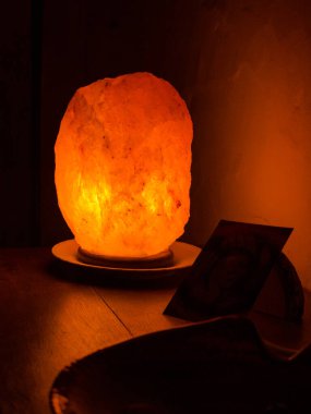 turuncu ışıklı tuz lambası ahşap rafta.