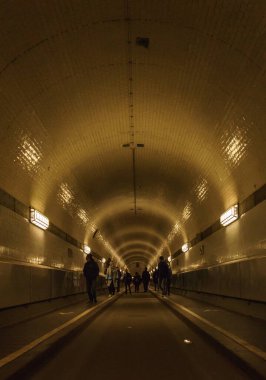 Hamburg 'da nehir elpinin altındaki tarihi tünelde yürüyen insanların siluetleri.