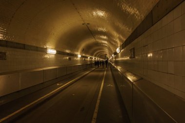 Hamburg 'da nehir elpinin altındaki tarihi tünelde yürüyen insanların siluetleri.