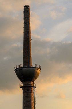 Akşamları altın güneş ışığı altında eski tuğla fabrikası bacası
