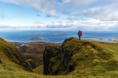 İskoçya, Quiraing 'deki Skye Adası' nda bir uçurumun kenarında duran adam denizi izliyor.
