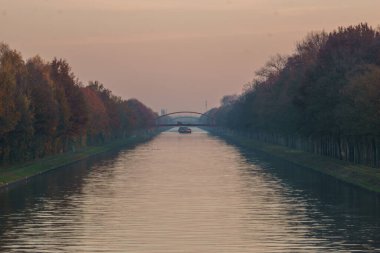 Sonbahar akşamı uzun ve düz bir kanalın üzerinden köprü manzarası