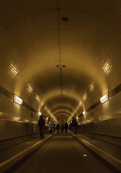 ハンブルクのエルベ川の下の歴史的な古いトンネルを歩く人々のシルエットは — ストック写真