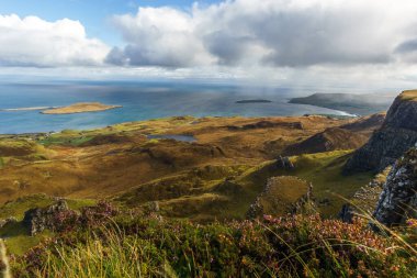 Kayalarla, göllerle ve denizlerle dolu bir manzaranın üzerinde mavi bulutlu gökyüzü, Skye Adası, İskoçya