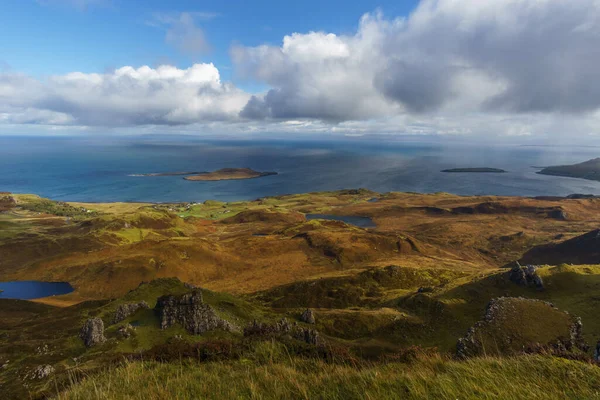 Kayalarla, göllerle ve denizlerle dolu bir manzaranın üzerinde mavi bulutlu gökyüzü, Skye Adası, İskoçya