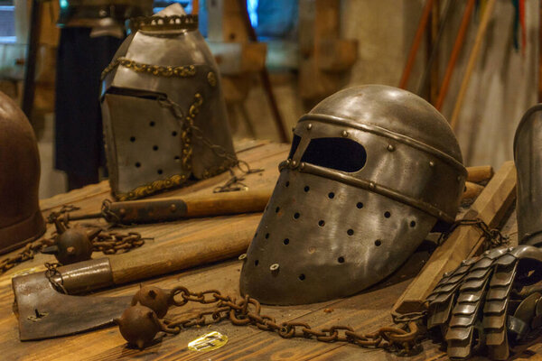 Metal helmet of medivial knight, ax and morning star on table
