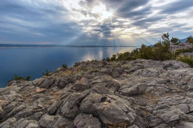 Güneş ışınları Hırvat denizinin üzerinden bulutların arasından geçiyor