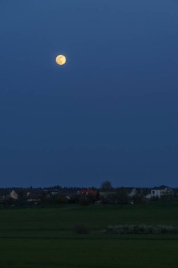 Köyün dışında mavi saatte, kırsal alanda dolunay.