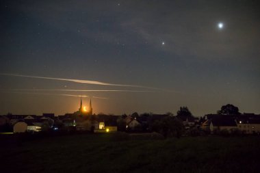 Hilal ay, Alman köyünün iki kulesi arasında yükseliyor. Mars, Jüpiter ve Satürn 'le birlikte.