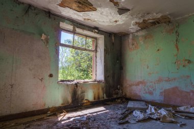 Eski duvar kâğıdı ve ahşap zemini olan yıkılmış bir evde terk edilmiş bir oda.