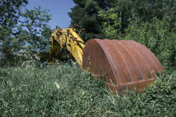 废弃的旧挖掘机 前面有一把生锈的大铲子 四周环绕着绿色的植物 — 图库照片