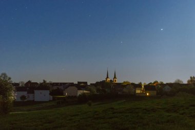 Yükselen Mars, Jüpiter ve Satürn gezegenleri şafak vakti Eifel 'deki Alman köyünün üzerinde.