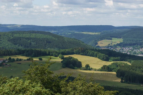 Eifel 'deki ormanın yanı sıra eğri büğrü saman balyalarıyla hasat edilen alan, Almanya, Gerolstein