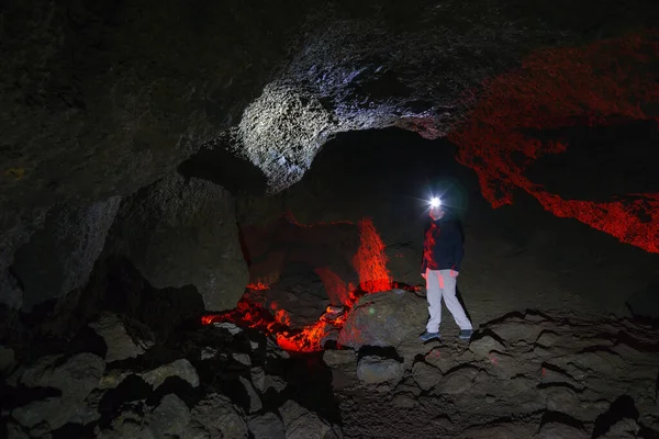 man exploring dark cave with headlight