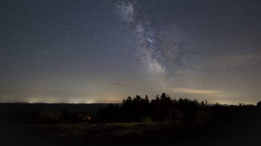 Samanyolu 'nun galaktik çekirdeği Schliffkopf, Kara Orman, Almanya' daki ağaçların siluetinin üzerinde.